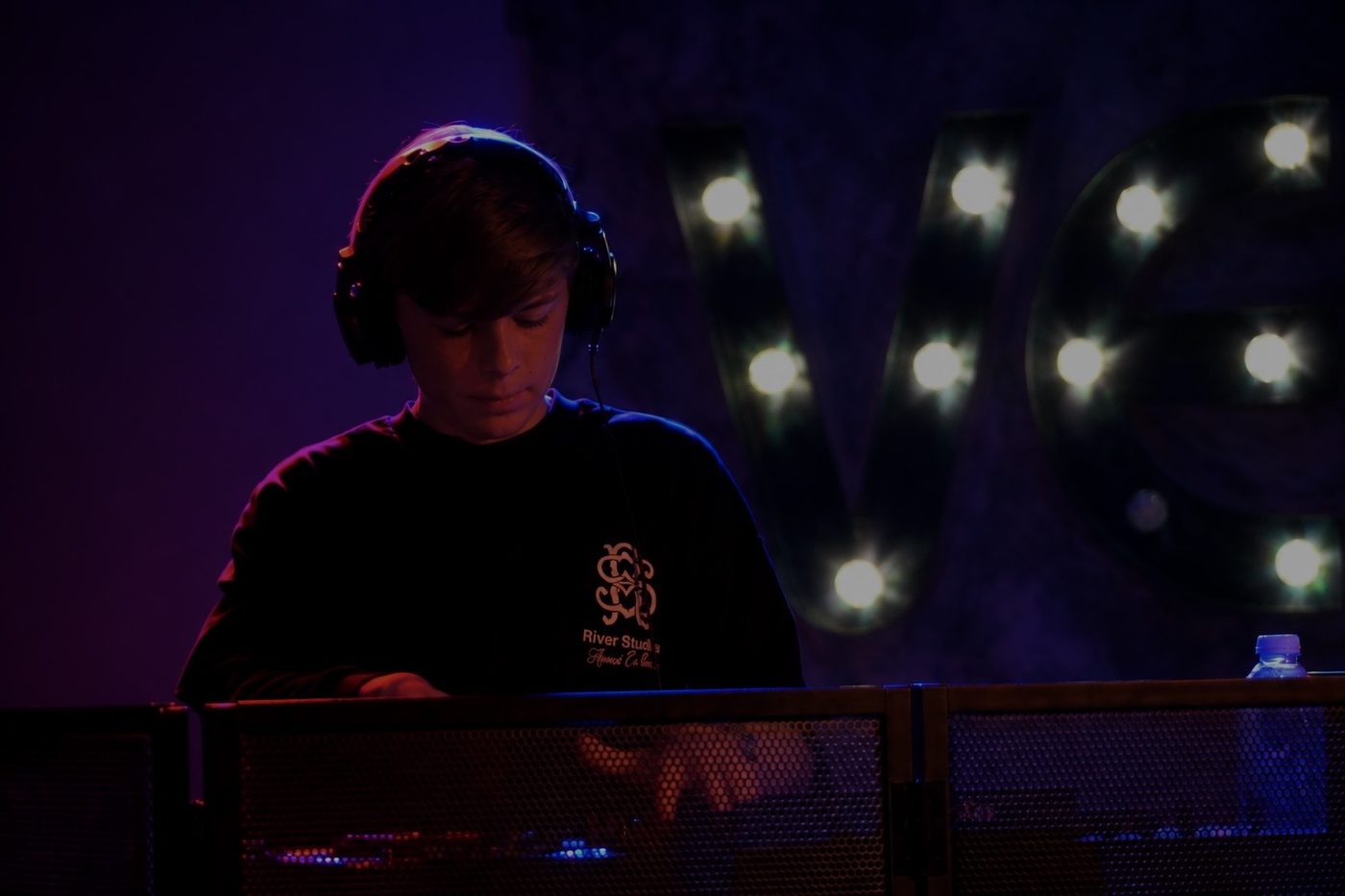 Oliver Newton concentrating on the decks under purple stage lights